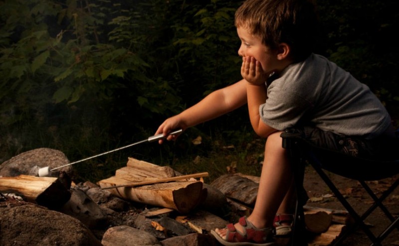 A boy sitting next to a campfire